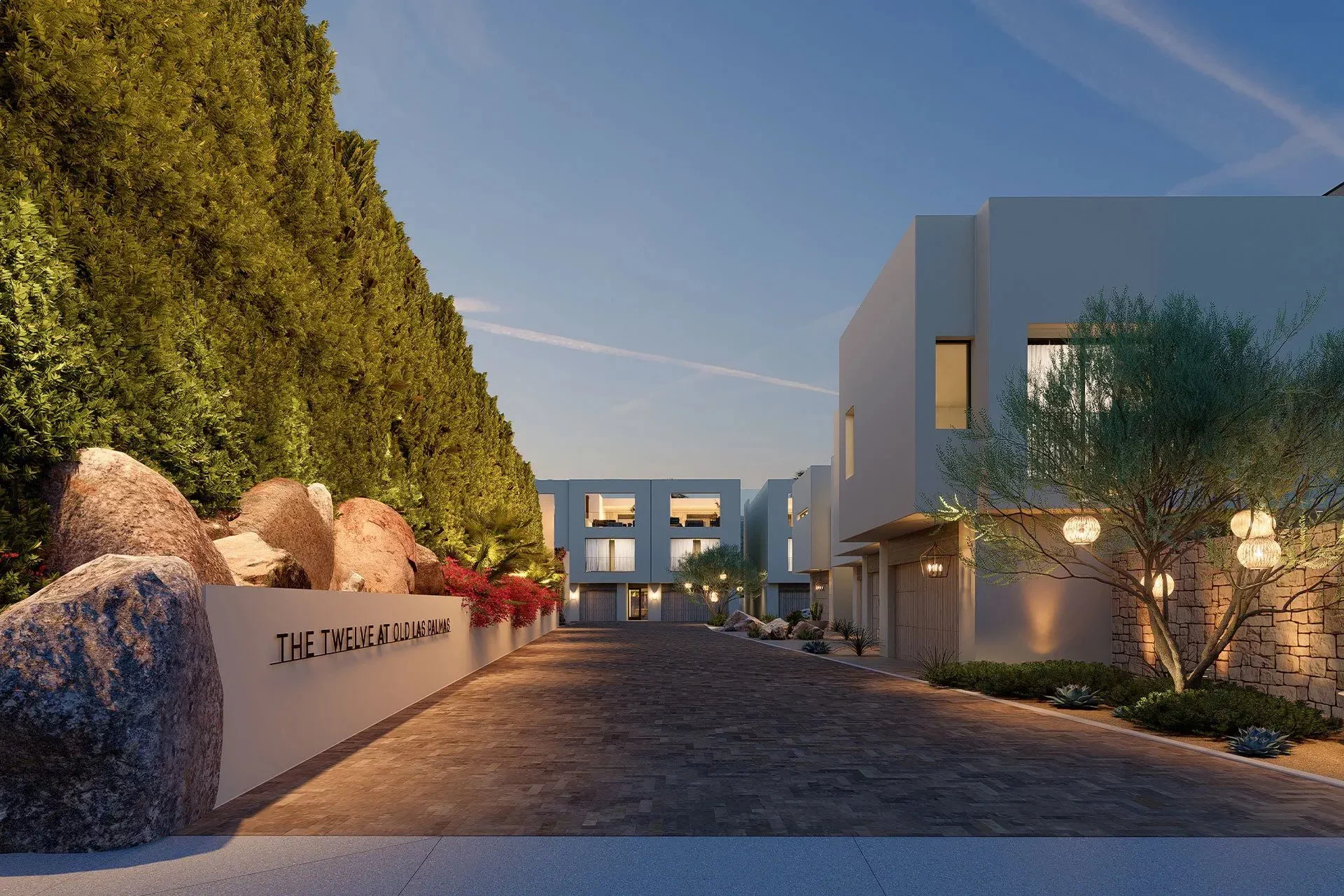 A lit private drive between townhomes at dusk